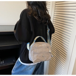 Detailed side view of multi-compartment nylon crossbody bag with patterned shoulder strap