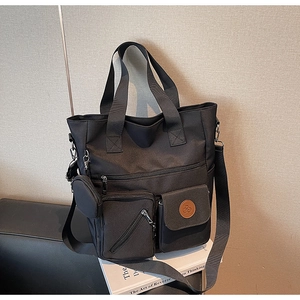 Close-up of black canvas tote bag with multiple pockets and a small round coin purse charm