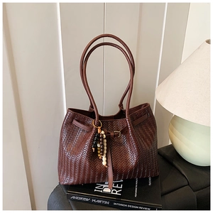 Détail de la texture tressée marron foncé du sac cabas avec pompon perlé