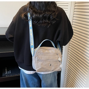 Detail of khaki nylon crossbody bag with multi-zip pockets and jacquard wide strap