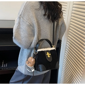 Close-up of black suede crossbody bucket bag with white faux fur trim and gold lock