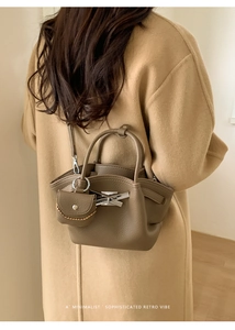 Detail of olive green leather bucket bag with metal buckle on wool coat outfit