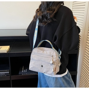 Detail of grey nylon crossbody bag featuring multiple pockets and jacquard wide strap