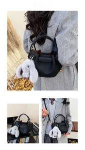 Detail of black pebbled leather bucket bag with metal buckle and grey rabbit plush pendant