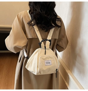 Detail of a beige canvas triangle backpack with a black and white woven rope handle