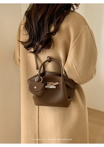 Detail view of dark brown pebbled leather underarm bag with silver cross buckle and mini pouch