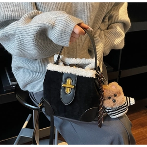 Detail of suede bucket bag featuring faux shearling trim and a golden twist lock closure
