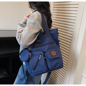 Detail of blue nylon tote bag with functional pockets and round coin purse pendant