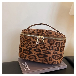 Détail de la trousse à maquillage léopard avec double zip doré et poignée de transport