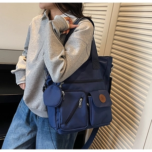 Detail of navy canvas tote bag with multiple zip pockets and hanging round coin purse