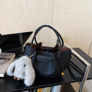 Detail of black pebbled leather bucket bag with drawstring and plush rabbit charm