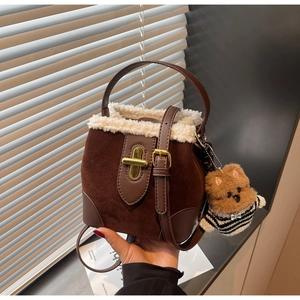 Detail of suede bucket bag with white faux fur trim, gold lock and cute dog charm