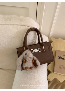 Detail of retro dark brown leather crossbody bag with heart buckle and rabbit pendant