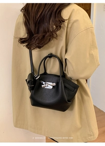Side view of black lychee grain leather bucket bag with silver metal buckle on a model