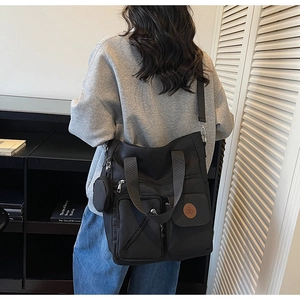 Detail of black multi-pocket nylon tote bag with coin purse charm and adjustable strap