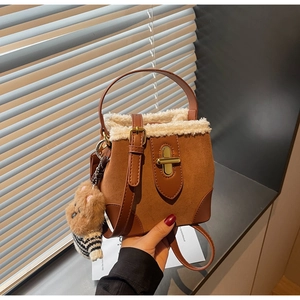 Close-up of brown faux suede bucket bag with plush white trim and cute bear charm