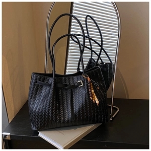Détail du sac cabas tressé noir avec boucle métallique et breloque en perles