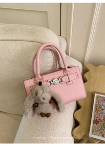 Detailed view of pink lychee leather bag with gray plush bunny charm and silver heart clasp