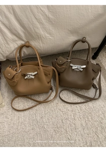 Detail of minimalist bucket bags with silver bow clasp and mini decorative pouch