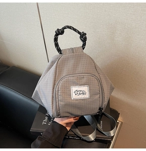 Detail of grey plaid canvas backpack featuring Muran Bags woven label and rope handle