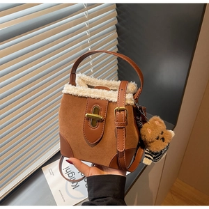 Detail of suede bucket bag featuring faux shearling trim and cute bear charm accessory