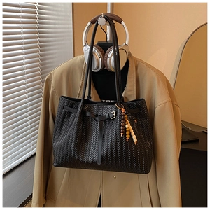 Détail de la texture tressée noire du sac fourre-tout avec pendentif en perles de bois