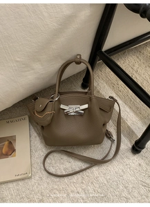 Detail of brown litchi pattern leather bag with silver bow buckle and small coin purse