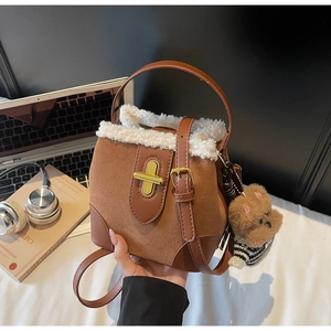 Detailed shot of brown suede bucket bag with white fleece trim and cute bear charm