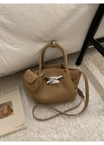Detail of khaki litchi grain underarm bag with silver lock and mini pouch charm