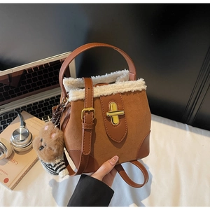 Detailed view of suede bucket bag with faux fur trim, golden twist lock, and bear charm