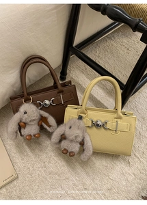 Detail of luxury textured leather handbags with heart metal locks and plush bunny charms