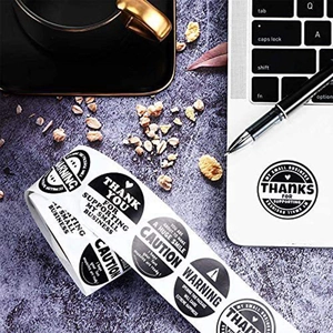 Roll of aesthetic Thank You and Warning business stickers for packaging on office desk