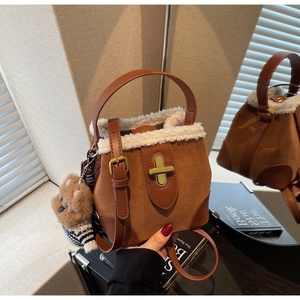 Detail of suede bucket bag with faux fur trim, gold lock, and plush bear charm