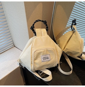 Detail of checkered cream crossbody bag with woven handle and front zipper pocket