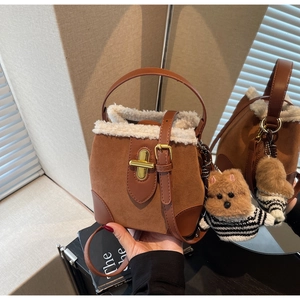 Macro shot of brown suede bucket bag with white fleece trim and gold clasp detail