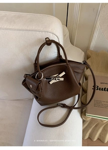 Detail of silver bamboo-style clasp on a dark brown lychee leather bucket bag