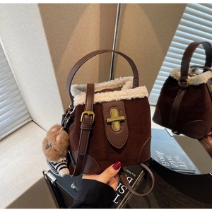 Detail of suede bucket bag featuring faux shearling trim, gold clasp, and cute bear charm