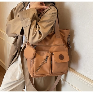Detail of khaki nylon tote bag featuring functional external pockets and small round pouch