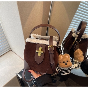 Close-up of brown suede bucket bag with fluffy white trim and golden metal clasp