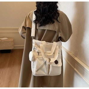 Detail of cream large tote bag with utility pockets and a round coin purse attached