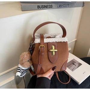 Brown suede bucket bag detail with white faux fur trim and cute bear charm accessory