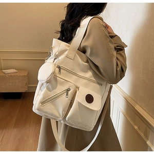 Detail of off-white canvas tote bag with multiple functional pockets and cherry logo