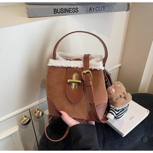 Close-up of brown suede bucket bag with white fleece trim and gold metal twist lock