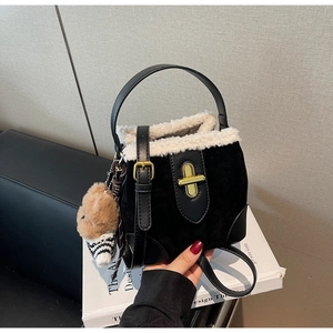 Detail of black suede bucket bag with faux shearling trim and teddy bear charm