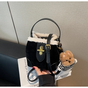 Detail of black suede bucket bag with white faux fur trim and cute puppy charm