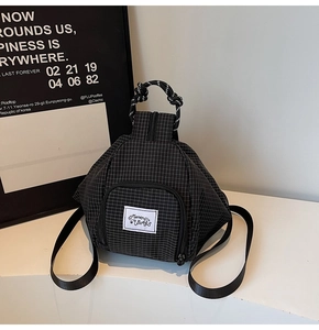 Detail of black checkered nylon backpack with unique triangular structure and woven handle