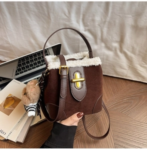 Detailed view of a brown suede bucket bag with white faux fur trim and cute bear charm