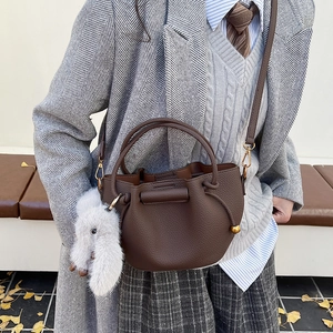 Close-up of a brown lychee pattern bucket bag with a white plush bunny charm accessory