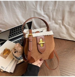 Detail of suede bucket bag featuring faux fur trim and a cute teddy bear charm accessory
