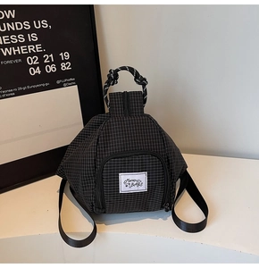 Close-up of black and white plaid pattern backpack with unique triangle shape and logo tag